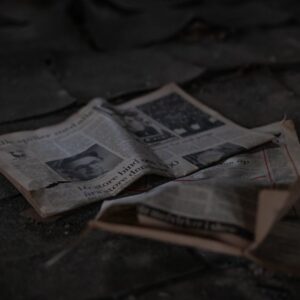 Scattered newspapers on an outdoor pavement, showcasing decay and abandonment.