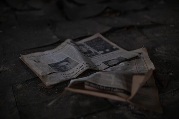 Scattered newspapers on an outdoor pavement, showcasing decay and abandonment.