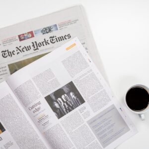 Flat lay of a coffee cup and The New York Times newspaper, ideal for business and lifestyle themes.